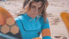 Retrato de la surfista portuguesa Joana Andrade, con un neopreno en tonos naranjas y azules, en la playa. 