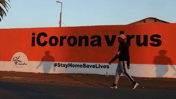 FILE PHOTO: A man walks past the words &quot;Coronavirus&quot;  painted on a wall, amid the spread of the coronavirus disease (COVID-19) outbreak, in Soweto, South Africa, May 31, 2020. REUTERS/Siphiwe Sibeko/File Photo