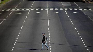 A man walks across an empty road in Buenos Aires, Argentina, Monday, March 23, 2020. The government has ordered a forced lock down until the end of the month to help contain the spread of the new coronavirus. (AP Photo/Natacha Pisarenko)