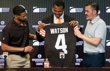 Mar 25, 2022; Berea, OH, USA;  Cleveland Browns quarterback Deshaun Watson looks at his new jersey along with general manager Andrew Berry, left and head coach Kevin Stefanski, right during a press conference at the CrossCountry Mortgage Campus. Mandatory Credit: Ken Blaze-USA TODAY Sports