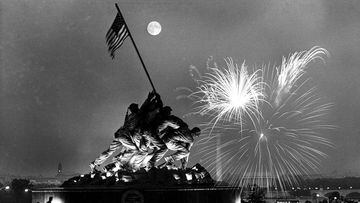 FILE - In this July 4, 1966 file photo, the moon shines above the United States Marine Corps War Memorial, which depicts a scene from Iwo Jima, as fireworks burst over Washington, seen from the Virginia side of the Potomac River. The Washington Monument a