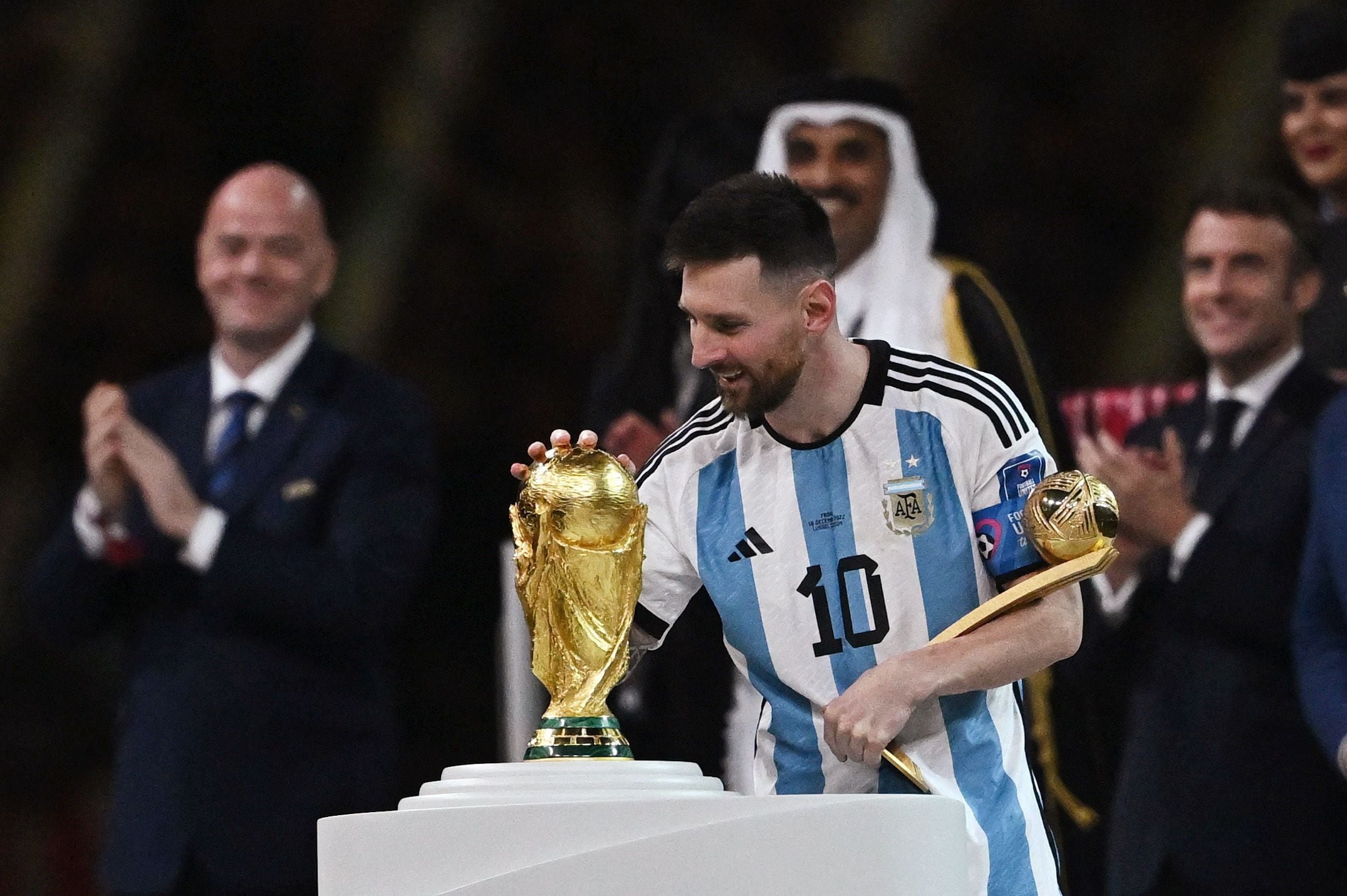 Soccer Football - FIFA World Cup Qatar 2022 - Final - Argentina v France - Lusail Stadium, Lusail, Qatar - December 18, 2022  Argentina's Lionel Messi touches the World Cup trophy after receiving the Golden Ball award REUTERS/Dylan Martinez