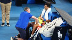 El tenista serbio Novak Djokovic recibe asistencia médica en su rodilla durante su partido ante Grigor Dimitrov en el Open de Australia.