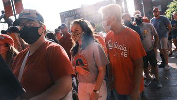 People, some in masks, head to a St. Louis Cardinals game.