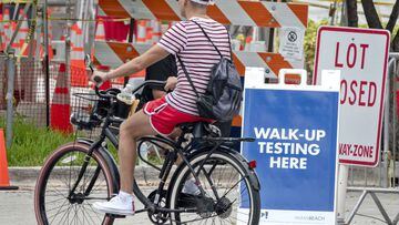 Miami (United States), 12/07/2020.- A men rides a bike in front of the walk-UP Coronavirus testing entrance in the Miami beach Convention Center in Miami Beach, Florida, USA, 12 July 2020. Florida reports 15,300 new Coronavirus cases, a record for one day