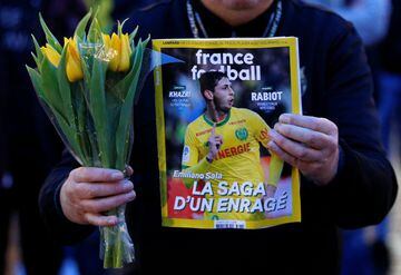 A man holds a sports magazine and yellow tulips as fans gather in Nantes' city center after news that newly-signed Cardiff City soccer player Emiliano Sala was missing after the light aircraft he was travelling in disappeared between France and England th