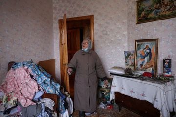 A woman surveys the damage in one of the rooms in her Kyiv home.