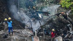 Firemen and rescue workers stand next to the debris of an IAF Mi-17V5 helicopter crash site in Coonoor, Tamil Nadu, on December 8, 2021. - A helicopter carrying India&#039;s defence chief General Bipin Rawat crashed, the air force said, with a government 