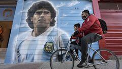 A man rides a bicycle past a mural painted by artist Marley outside the Diego Armando Maradona stadium as people are gathering to commemorate the Argentine legend&#039;s second goal against England during the FIFA World Cup Mexico 1986 on its 35th anniversary, in Buenos Aires on June 22, 2021. (Photo by Juan MABROMATA / AFP) / RESTRICTED TO EDITORIAL USE - MANDATORY MENTION OF THE ARTIST UPON PUBLICATION - TO ILLUSTRATE THE EVENT AS SPECIFIED IN THE CAPTION