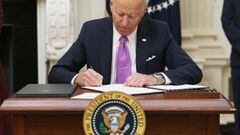 (FILES) In this file photo US President Joe Biden signs executive orders as part of the Covid-19 response in the State Dining Room of the White House in Washington, DC, on January 21, 2021. - More than 25 million Covid-19 cases have been recorded in the U
