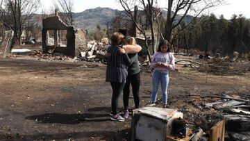 Women embrace after a forest fire in Las Golondrinas town, in Chubut province, Argentina, on March 11, 2021. - Seven people were injured and 15 more missing on Wednesday as forest fires ripped through Argentine Patagonia, official sources said. Some 200 people had to be evacuated and around 100 homes were damaged by fire in an area of forests and lakes popular with tourists close to the Andes mountain range. (Photo by FRM / AFP)
