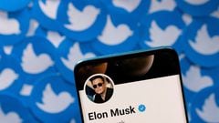 Elon Musk's Twitter profile is seen on a smartphone placed on printed Twitter logo.