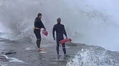Dos socorristas a punto de entrar al agua entre olas gigantes que rompen contra las rocas en Windansea Beach, San Diego (California, Estados Unidos), en enero del 2023. 
