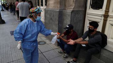 A health care worker sanitises people wearing face masks as they wait in line to be tested for the coronavirus disease (COVID-19) at the Colon Theatre, in Buenos Aires, Argentina April 13, 2021. REUTERS/Agustin Marcarian