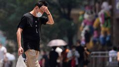 A man wearing face mask reacts on a street amid a heatwave warning, following the coronavirus disease (COVID-19) outbreak in Shanghai, China July 13, 2022. REUTERS/Aly Song