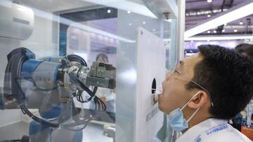 BEIJING, CHINA - AUGUST 18: A staff member takes part in a demonstration of a robot arm collecting swab samples for coronavirus disease (COVID-19) detection during the 2022 World Robot Conference at Beijing Etrong International Exhibition on August 18, 2022 in Beijing, China. The 2022 World Robot Conference kicked off on Thursday in Beijing. (Photo by Lintao Zhang/Getty Images)