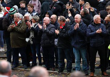 Los espectadores y aficionados presentan sus respetos en las afueras de Old Trafford mientras pasa el cortejo.