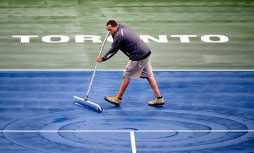 Un trabajador del estadio donde se disputa el torneo de tenis Rogers Cup de Toronto se afana en quitar el agua de la lluvia caída en la pista central. 