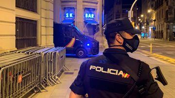 Un polic&iacute;a nacional patrullando por la calle de Barcelona, frente a la comisar&iacute;a de Via Laietena, con una furgoneta de antidisturbios al fondo. 