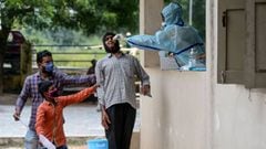 Residents hold a man as a health worker (R) collects a swab sample from him to test for the Covid-19 coronavirus at a community gym centre on the outskirts of Hyderabad on October 8, 2020. (Photo by NOAH SEELAM / AFP)