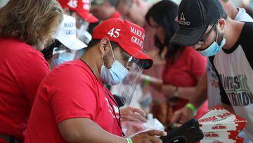 TULSA, OKLAHOMA - JUNE 20: Merchandise venders wear masks while selling campaign gear during a rally for U.S. President Donald Trump at the BOK Center on June 20, 2020 in Tulsa, Oklahoma. Trump is holding his first political rally since the start of the c