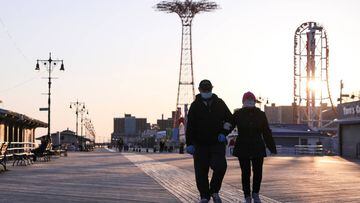People wearing protective masks walk past closed shops on the the Coney Island boardwalk during the outbreak of coronavirus disease (COVID-19) in Brooklyn, New York, U.S., April 11, 2020. Picture taken April 11, 2020. REUTERS/Caitlin Ochs