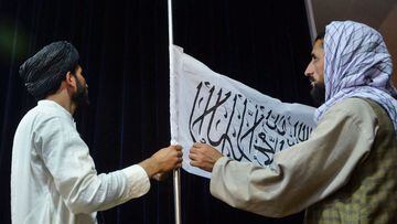 Men adjust the Taliban flag before the arrival of Taliban spokesperson Zabihullah Mujahid (unseen) to address the first press conference in Kabul on August 17, 2021 following the Taliban takeover of Afghanistan. 