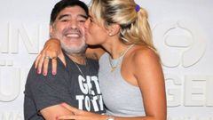Diego Armando Maradona sonriendo mientras su pareja, Roc&iacute;o Oliva, le da un beso en la mejilla.