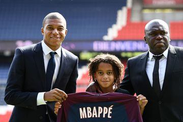 Paris Saint-Germain's new forward Kylian Mbappe (L) together with father Wilfried Mbappe and his brother Ethan holds his jersey during his presentation at the Parc des Princes stadium in Paris on September 6, 2017.