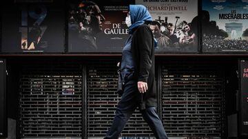 A woman walks past a closed cinema in Paris on April 20, 2020. 