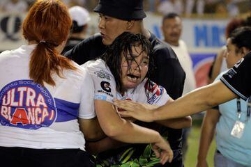 Una mujer es sostenida por otra mientras llora desconsoladamente tras una estampida durante el partido de fútbol entre Alianza y FAS en el estadio Cuscatlán en San Salvador.