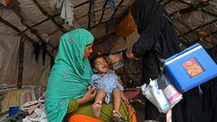 A health worker (R) administers polio vaccine drops to a child during a polio vaccination door-to-door campaign in LahorexA0on August 16, 2020. (Photo by Arif ALI / AFP)
