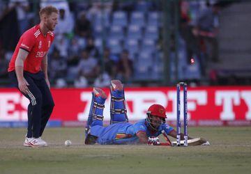 Afghanistan's Najibullah Zadran dives successfully to make his crease as England's Ben Stokes looks on.