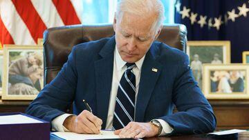 Joe Biden signs the American Rescue Plan on March 11, 2021, in the Oval Office of the White House in Washington, DC.