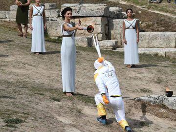 First Greek torchbearer for Pyeongchang 2018, cross-country skier Apostolos Angelis (2nd-R) receives the Olympic flame from actress Katerina Lechou (3rd-R) acting the high priestessat the Temple of Hera on October 23, 2017 during a dressed rehearsal of th