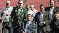 (FILES) This file photo taken on June 24, 2015 shows Former South African Rugby World Cup winner team Captain Francois Pienaar (L) assisting his former teammate flyhalf Joost van der Westhuizen (Front), during a re-enactement of the team photo from the 19