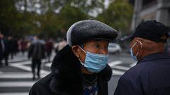 A man wearing a face mask crosses a street next to the Yangtze River in Wuhan on November 20, 2020. (Photo by Hector RETAMAL / AFP)