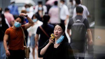 A woman wearing face mask uses a fan as she walks on a street on a hot day, following the coronavirus disease (COVID-19) outbreak in Shanghai, China July 19, 2022. REUTERS/Aly Song