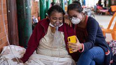A COVID-19 patient breathing with the assistance of oxygen and her daughter talk to relatives through a mobile phone at the regional hospital in Iquitos, the largest city in the Peruvian Amazon, on May 9, 2020 during the novel coronavirus pandemic. - Iquitos, one of the main sources of contagion for the new coronavirus in the country, desperately received an oxygen plant from Lima on Saturday to prevent the collapse of the health system in the impoverished region. &quot;People do not die from the coronavirus, but from lack of oxygen&quot;!, claims to AFP Spanish aid worker Geneva Pena. (Photo by Ginebra PENA / AFP)