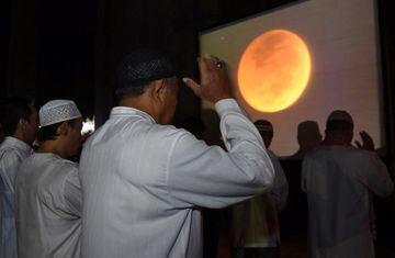 Imagen de un grupo de musulmanes indonesios rezando mientras se proyecta el eclipse lunar con luna de sangre 2018 en una pantalla en la mezquita Al-Akbar de Surabaya, Indonesia.