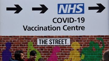 People walk past a direction sign for a covid-19 vaccination centre, amidst the easing of lockdown restrictions during the coronavirus pandemic, in London, Britain March 10, 2022. 