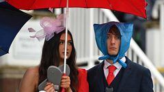 TOPSHOT - Racegoers shelter from the rain as they attend on the second day of the Grand National Festival horse race meeting at Aintree Racecourse in Liverpool, north-west England, on April 14, 2023. (Photo by Oli SCARFF / AFP)