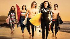 Los protagonistas de la serie de surf y adolescentes de Netflix Surviving Summer andando por la playa durante la puesta de sol. 