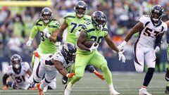 Rashaad Penny of the Seattle Seahawks carries the ball past Jonas Griffith of the Denver Broncos during the second quarter at Lumen Field on September 12, 2022 in Seattle, Washington.