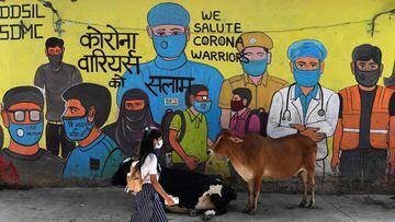 A girl walks past a mural representing frontline warriors of the Covid-19 coronavirus, painted on the wall of a dumping ground in New Delhi on September 29, 2020. (Photo by Sajjad  HUSSAIN / AFP)