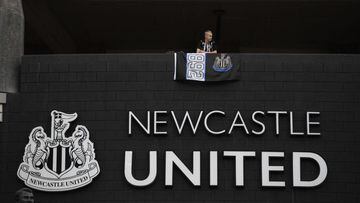 A Newcastle United football club supporter stands with a flag above the club logo at their stadium St James&#039; Park in Newcastle upon Tyne in northeast England on October 8, 2021. - A Saudi-led consortium completed its takeover of Premier League club N