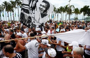 Fans carry flags with the picture of football legend Pelé during the funeral procession as his coffin is transported through the streets of Santos on the way to Pelé’s  final resting place at Memorial Necrópole Ecumênica cemetery.