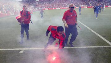 Groundsmen collect the flares thrown onto the pitch