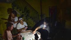 People play dominoes by flashlight during a blackout in Havana, Cuba, Wednesday, Sept. 28, 2022. Cuba remained in the dark early Wednesday after Hurricane Ian knocked out its power grid and devastated some of the country's most important tobacco farms when it hit the island's western tip as a major storm. (AP Photo/Ramon Espinosa)