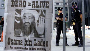 New York police stand near a wanted poster printed on a full page of a New York newspaper for Saudi-born militant Osama bin Laden, in the financial district of New York.